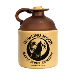 A close-up product photo of a Howling Moon Maple Syrup ceramic jug featuring a black howling wolf logo and cork stopper.