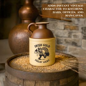 Irish Gold “Feelin’ Lucky” stoneware moonshine jug displayed on a whiskey barrel with grain and a copper still in the background, showcasing vintage Irish-themed bar décor.