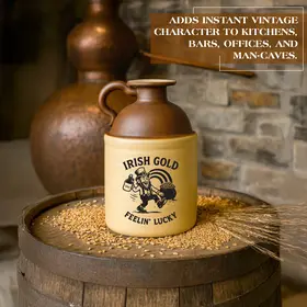 Irish Gold “Feelin’ Lucky” stoneware moonshine jug displayed on a whiskey barrel with grain and a copper still in the background, showcasing vintage Irish-themed bar décor.