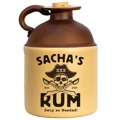 Ceramic rum jug with brown top, beige body, cork stopper, and pirate-themed design featuring skull in hat, crossed swords, and text ‘Sacha’s Rum, Est. 2020, Swig as needed.’ Rustic novelty drinkware.
