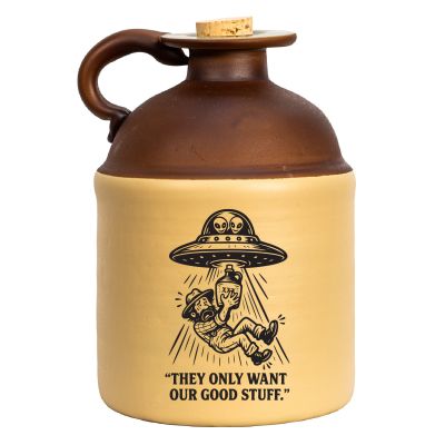 Alien-abduction stoneware moonshine jug featuring a UFO beaming up a moonshiner with the caption “They Only Want Our Good Stuff,” shown against a white background.