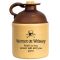Vintage-style ceramic moonshine jug with brown top and beige body featuring skull-and-crossbones graphic and humorous text reading ‘Women or Whiskey, hard to say which will kill you first.’ Rustic collectible whiskey jug with cork stopper